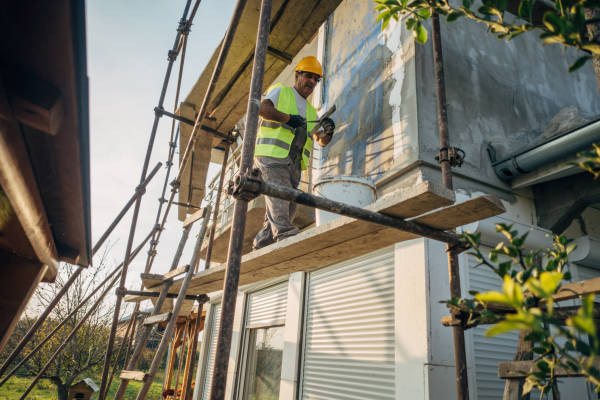 Artisan peintre réalisant un ravalement de façade et une application de peinture extérieure protectrice